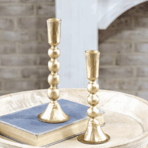 Two elegant gold candlesticks on a table with books.